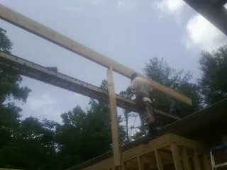 Carpenter setting a ridge beam over a new addition frame — Ice Dam Removal by Roofing Brothers in Carle Place