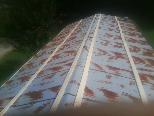 Rusted metal roof panels with new wood purlins before replacement — Storm Damage Roof Repair in Carle Place by Roofing Brothers