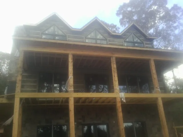 Dormers and porch framing on a large log home under construction — Roof Coating work by our crew in Carle Place