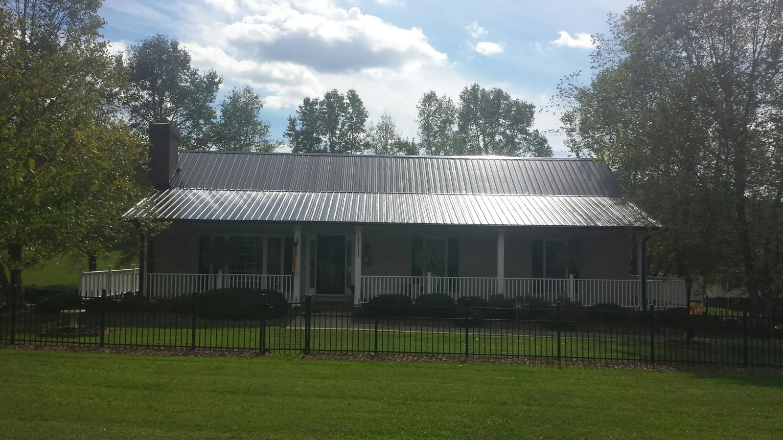 Gray metal roof on a brick ranch with a full width front porch — Gutter Guard Installation work by our crew in Carle Place