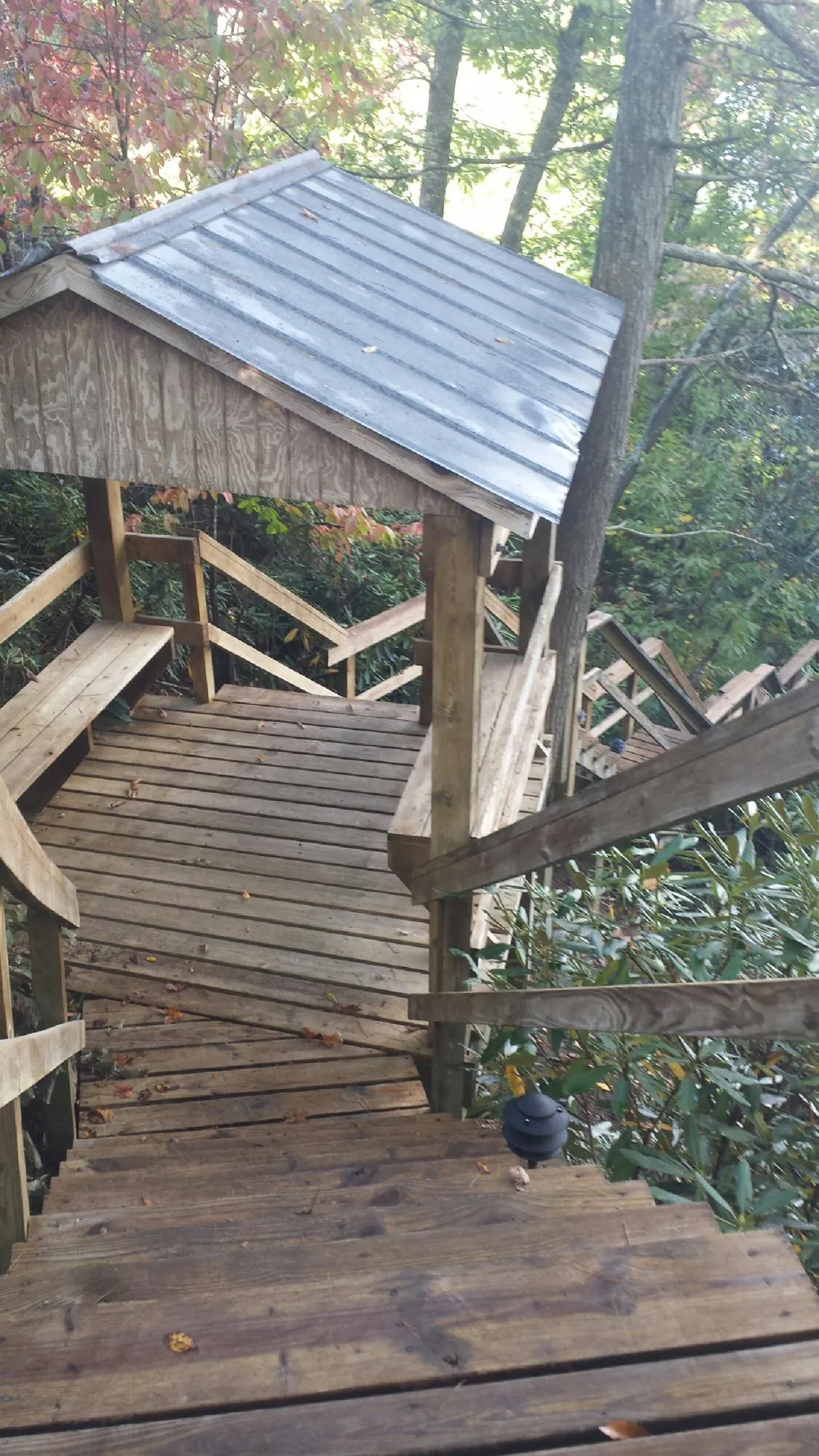 Metal roofed shelter over wooden steps on a wooded walkway — Skylight Repair & Installation work by our crew in Carle Place