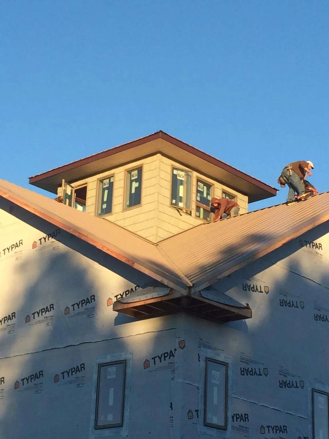 Roofers working around a rooftop cupola on a new metal roof at sunset — Roof Waterproofing in Carle Place by Roofing Brothers